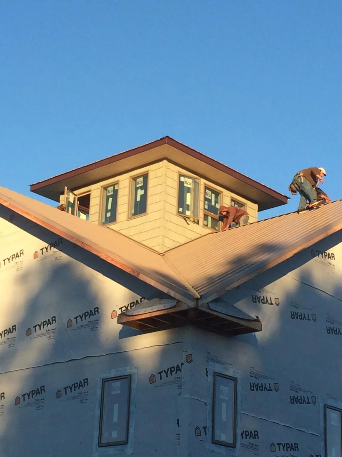 Roofers working around a rooftop cupola on a new metal roof at sunset — Roof Waterproofing in Rogersville by Roofing Brothers